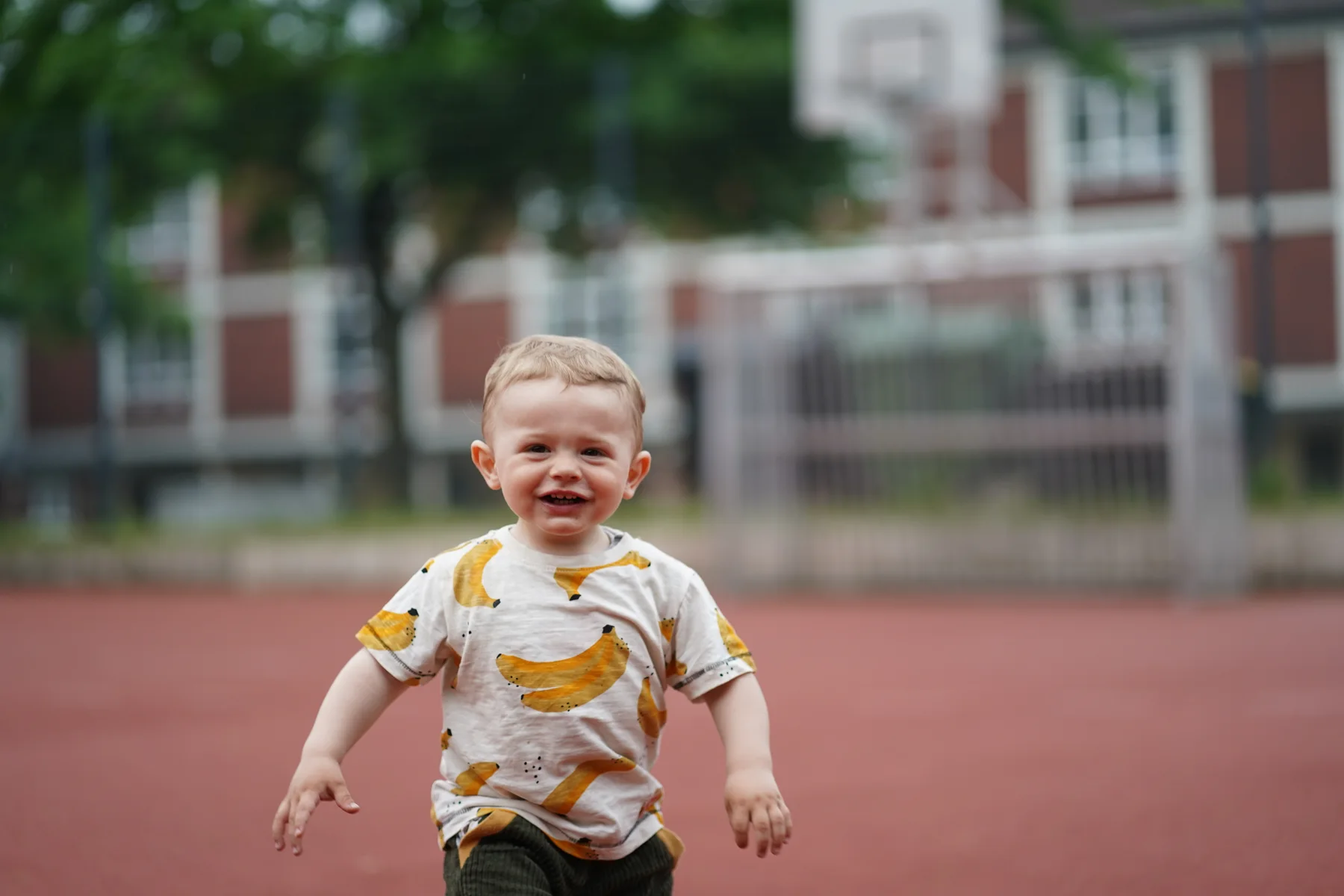 Lachender Junge rennt über einen Sportplatz auf die Kamera zu